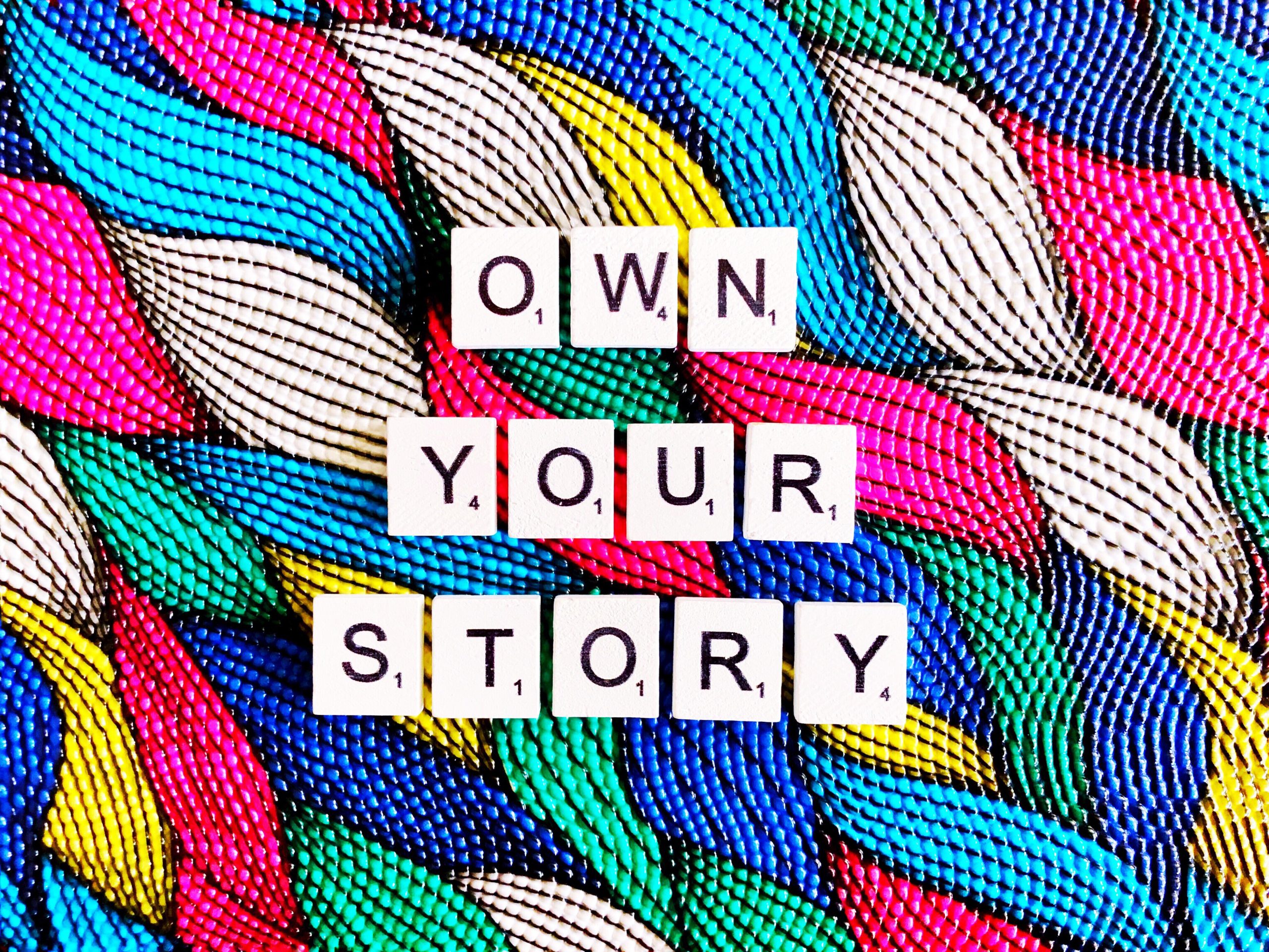 Scrabble tiles spelling 'own your story'
