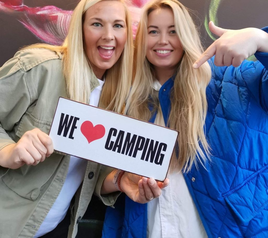 Campall founders Heidi Uhlgren Gudmestad and Silje Bjelland holding a 'We Love Camping' sign