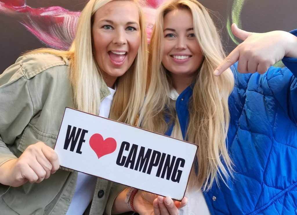 Campall founders Heidi Uhlgren Gudmestad and Silje Bjelland holding a 'We Love Camping' sign