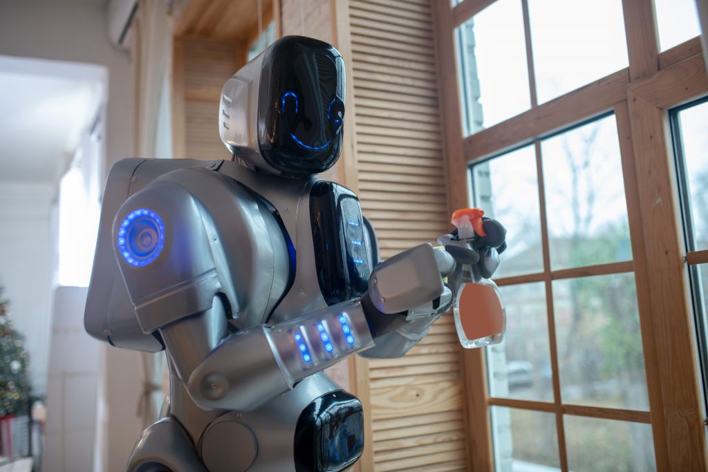 Robot with spray in hands cleaning the window in the kitchen