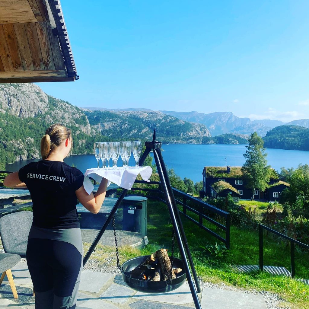 Waitress holding a tray of champagne glasses by a fjord