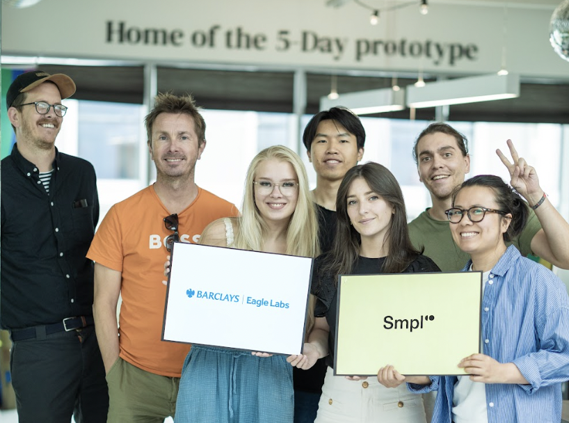 The SmplCo UX design team in our office holding Barclays and SmplCo logos